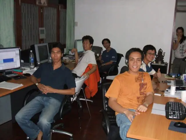 The Bangkok team at their computers, one smiling at the camera