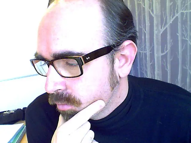 A team member in glasses striking a thoughtful pose at the webcam