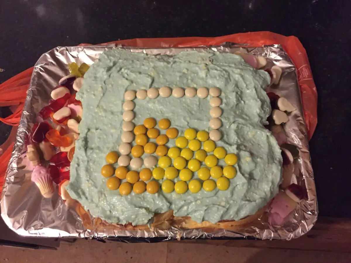 A homemade cake iced as the ScreenCloud logo in yellow sweets