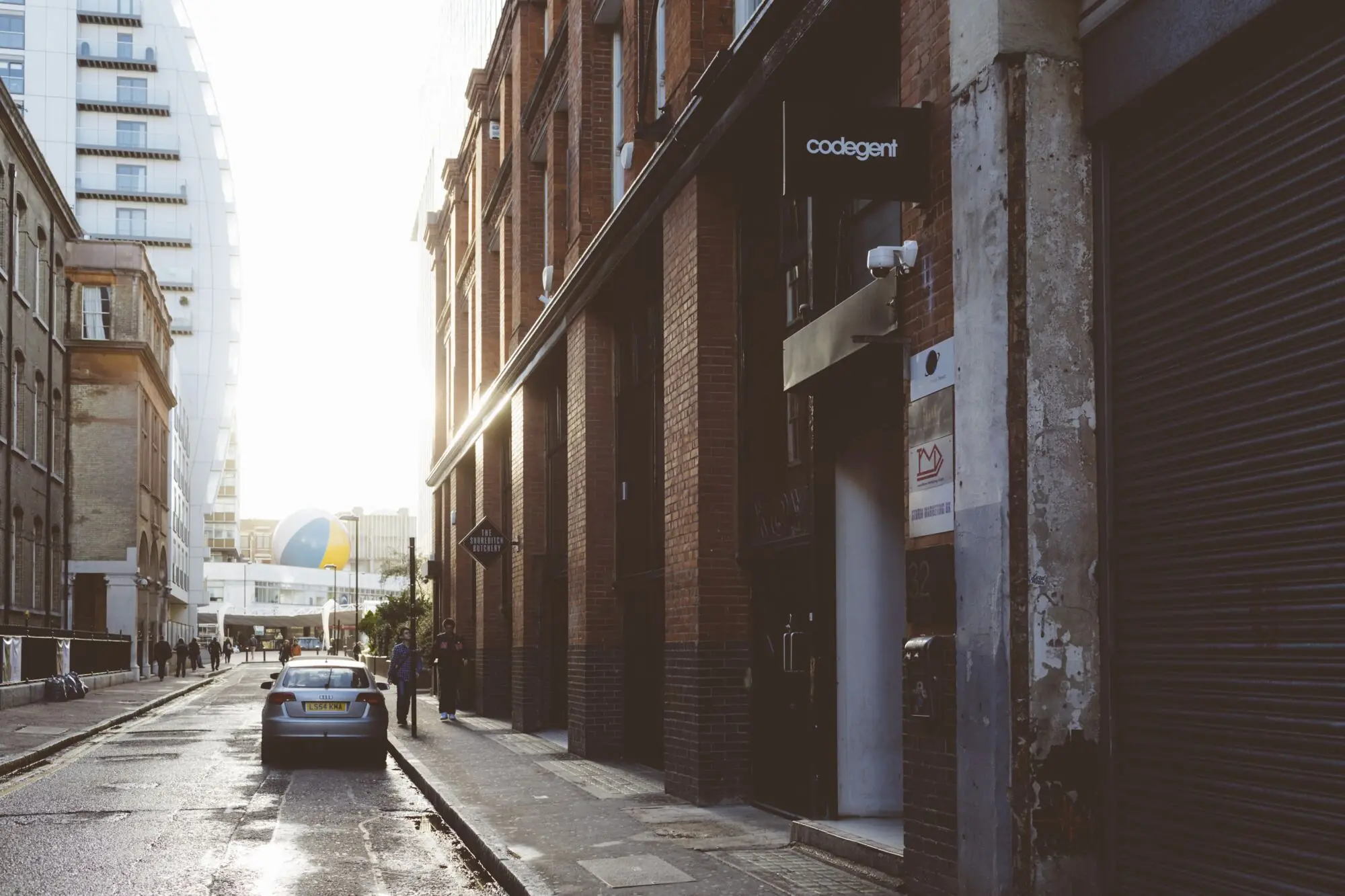 Cowper Street at low sun, the brick warehouse with the Codegent sign projecting over a wet road