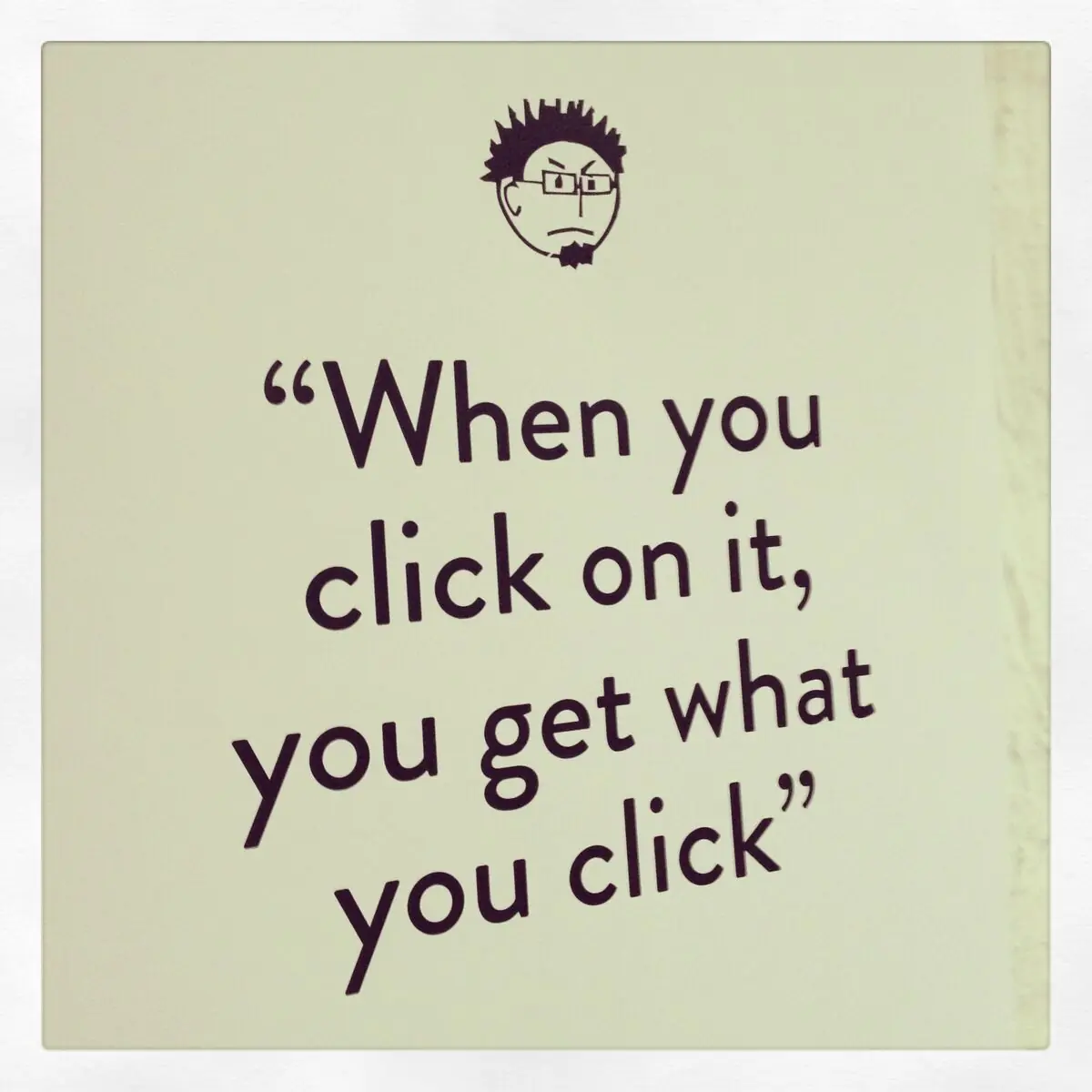 A poster on the studio wall with a cartoon face and the line: When you click on it, you get what you click