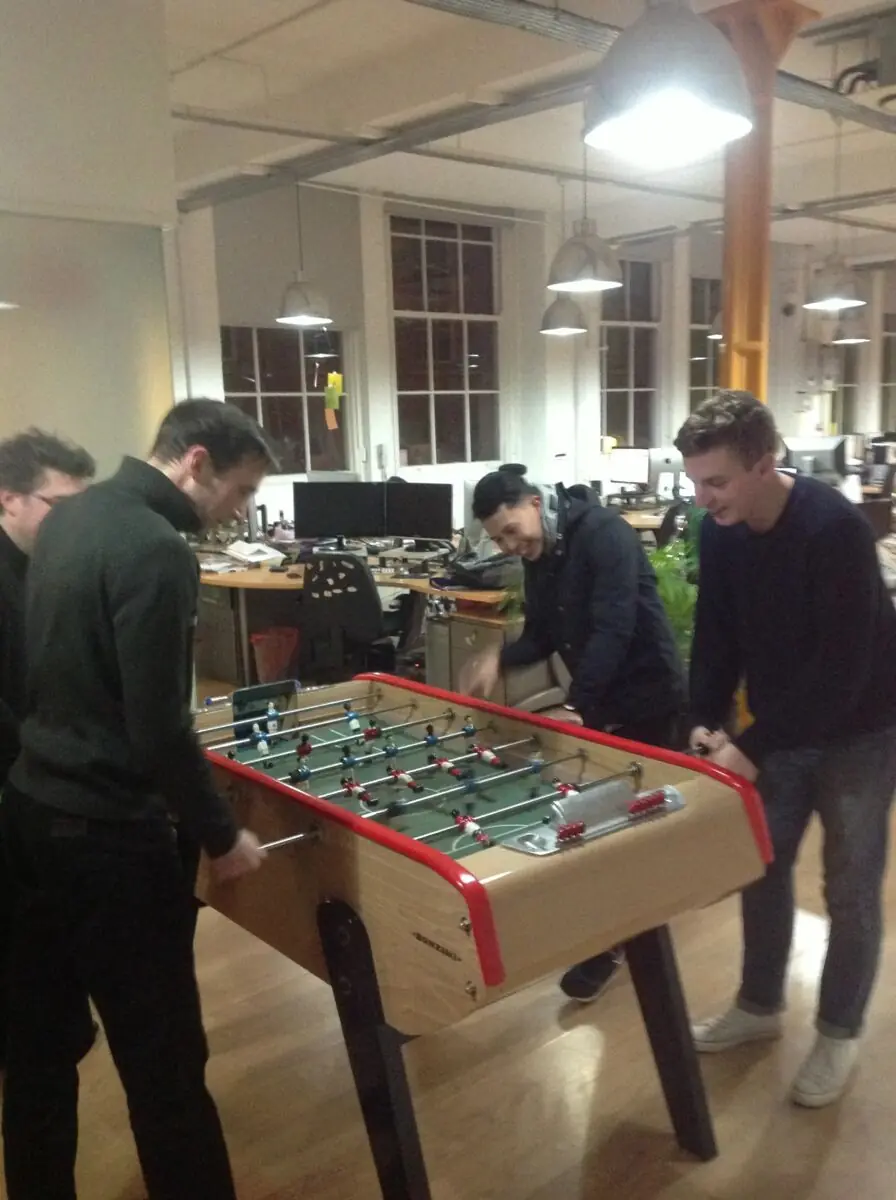 Four of the team playing table football in the studio after hours