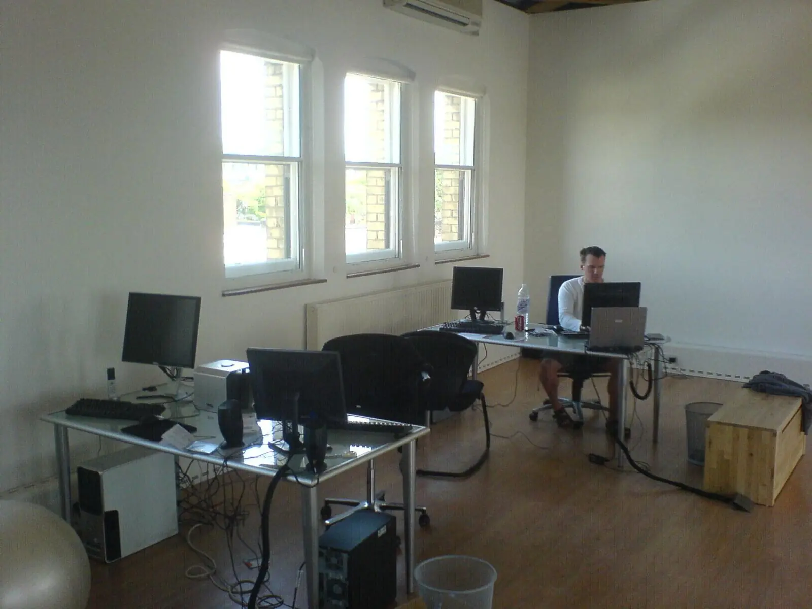 The new Clapham studio: white walls, three tall sash windows, glass desks and one person working at the back